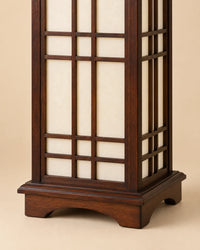 Détail du socle en bois marron et des panneaux translucides de la lampe Shoji