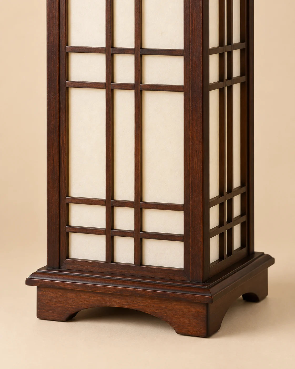 Détail du socle en bois marron et des panneaux translucides de la lampe Shoji